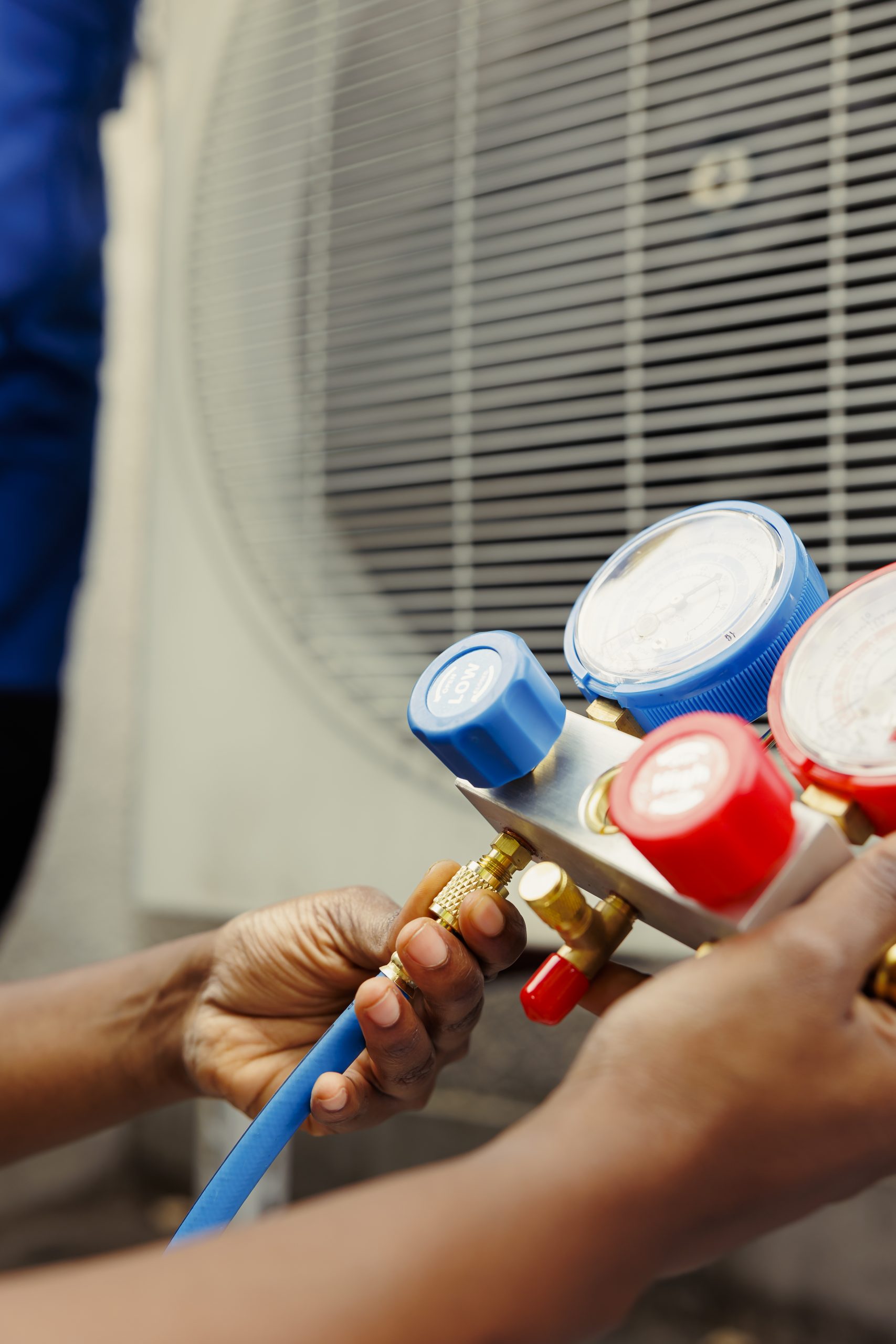 Close up of competent mechanic holding manometers used for checking hvac system refrigerant. Expert repairman using manifold indicators to check high or low freon levels of air conditioner tank